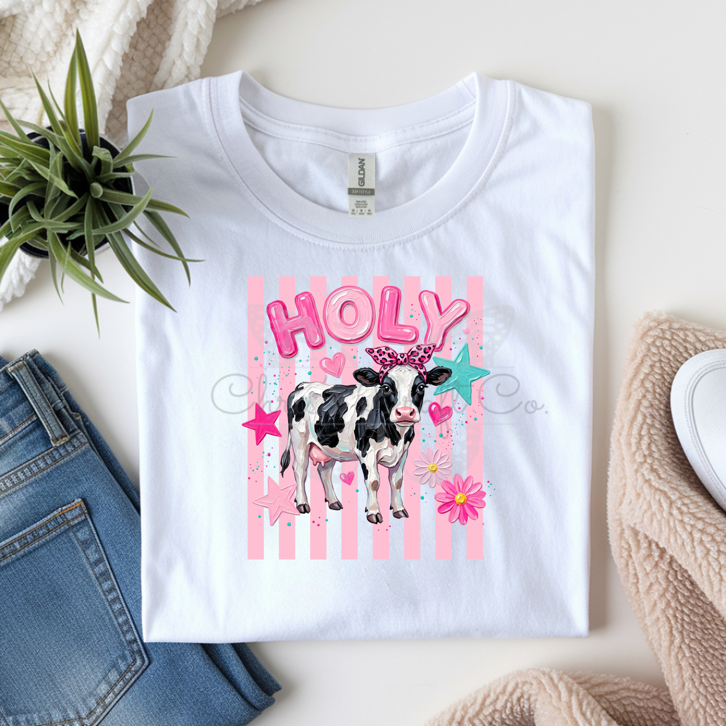 MOCK UP OF A Ready to press DTF apparel transfer on a hot pink t-shirt featuring a black-and-white country cow with a pink leopard bow, pink bubble letters, and a turquoise star backdrop.