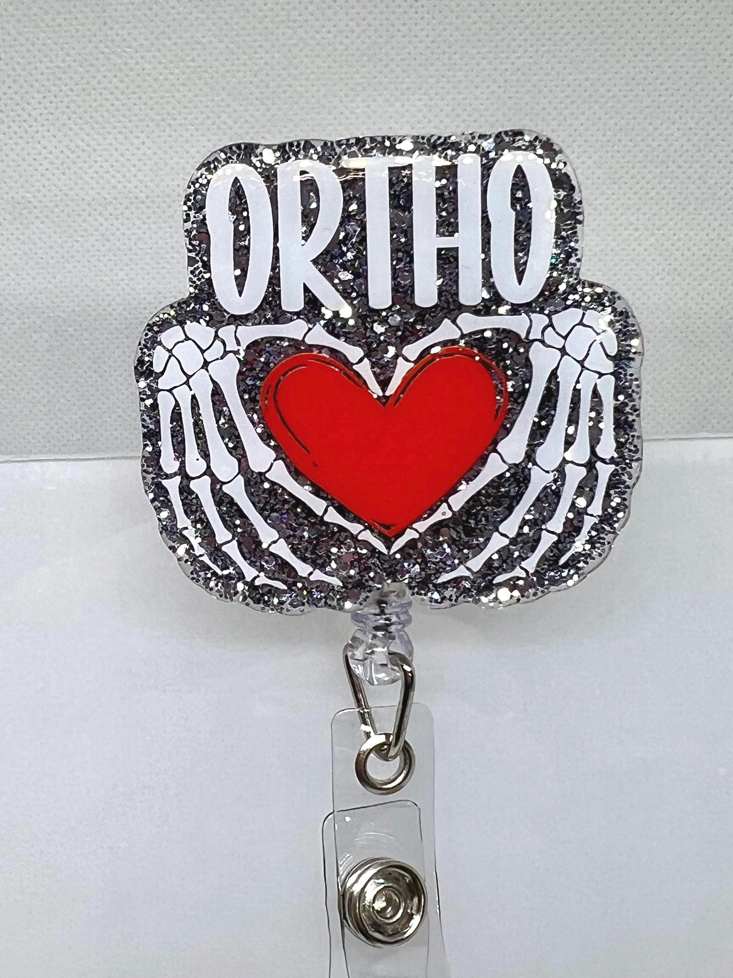 Glittery Orthopedic Badge Reel – Skeletal Hands Forming a Heart with 'ORTHO' Design, Perfect for Nurses, Doctors, and Medical Professionals
