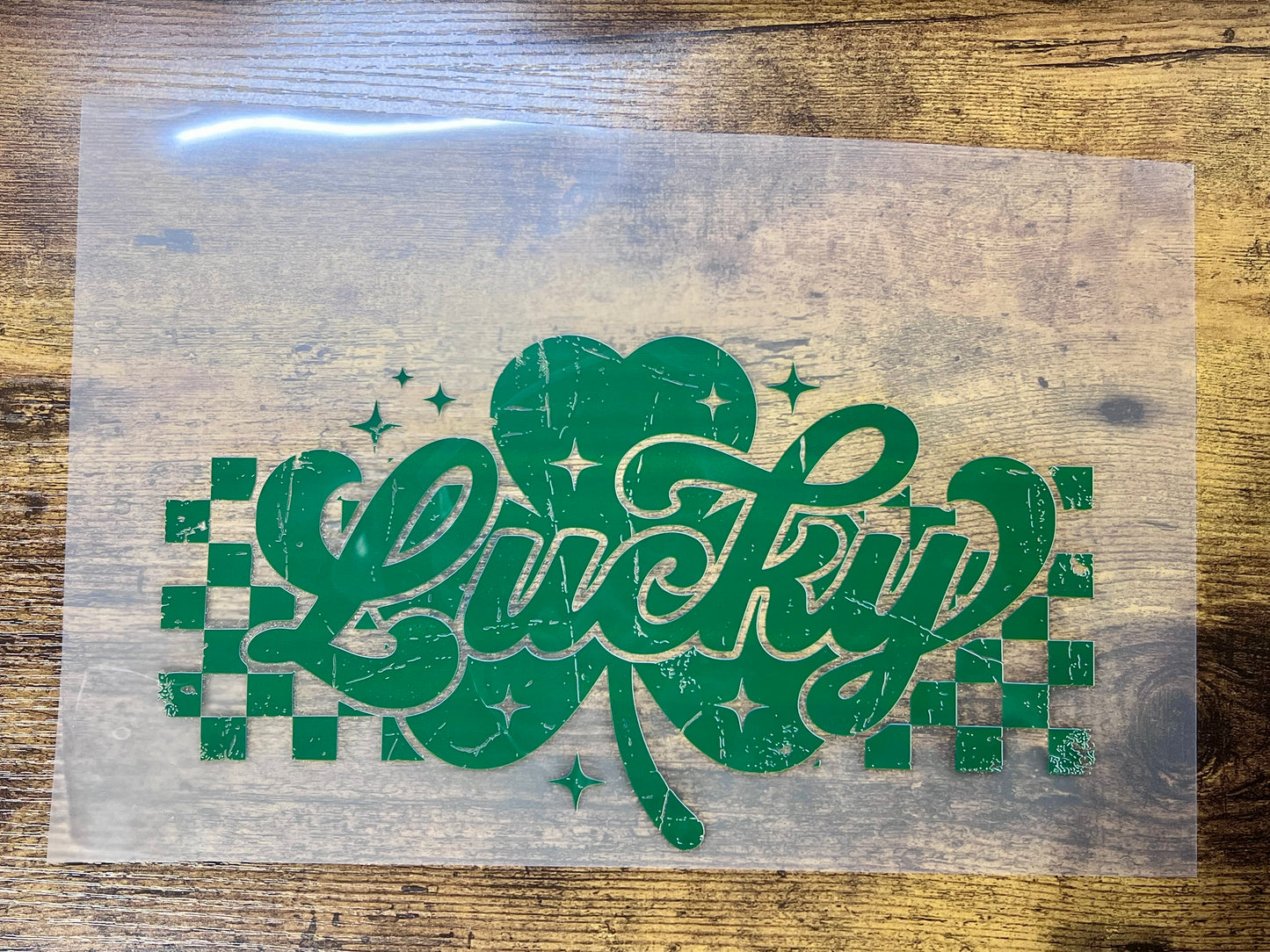 Retro Lucky shamrock heat transfer, white distressed clover graphic with checkerboard accents for ready-to-press apparel.