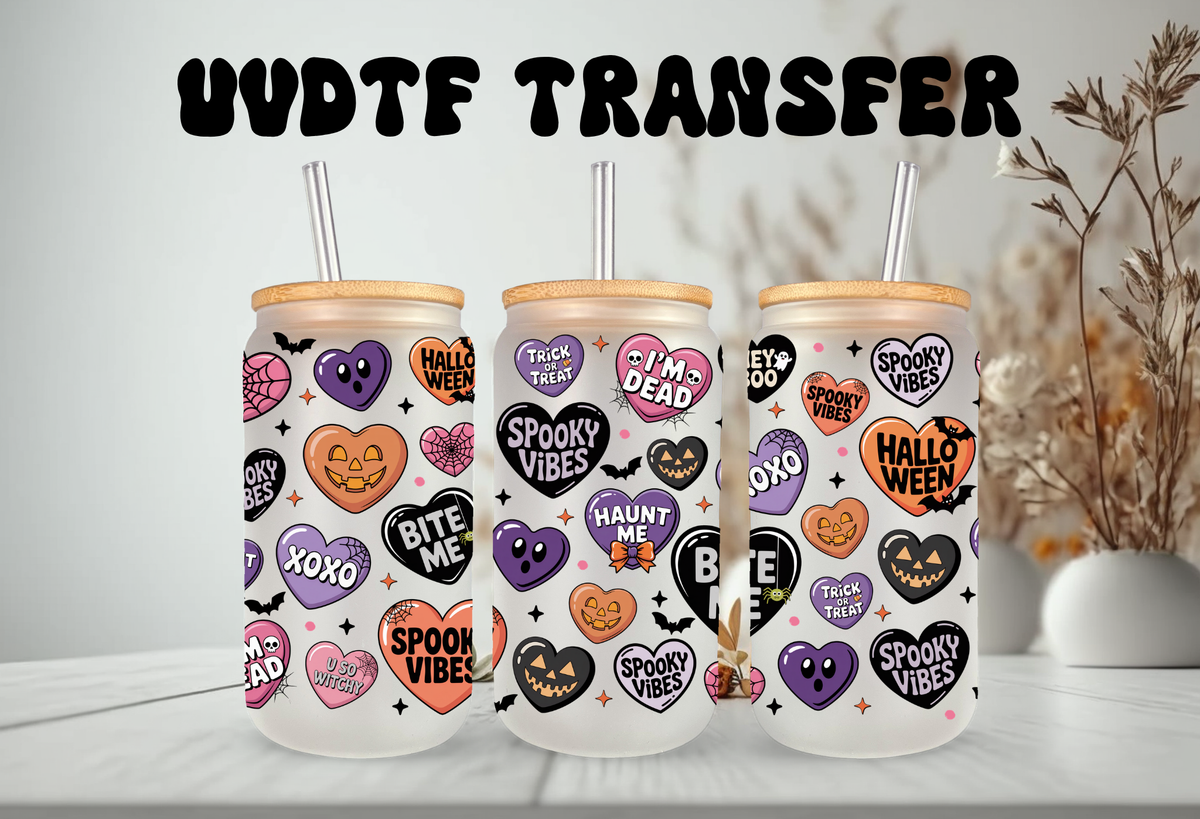 MOCKUP OF Clear glass 16oz can tumbler with a bamboo lid and glass straw, decorated with a pastel Halloween conversation hearts UVDTF wrap featuring phrases like Spooky Babe and Bite Me, displayed alongside iced drinks and fall decorations.