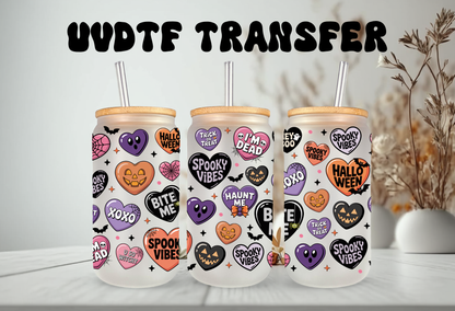 MOCKUP OF Clear glass 16oz can tumbler with a bamboo lid and glass straw, decorated with a pastel Halloween conversation hearts UVDTF wrap featuring phrases like Spooky Babe and Bite Me, displayed alongside iced drinks and fall decorations.