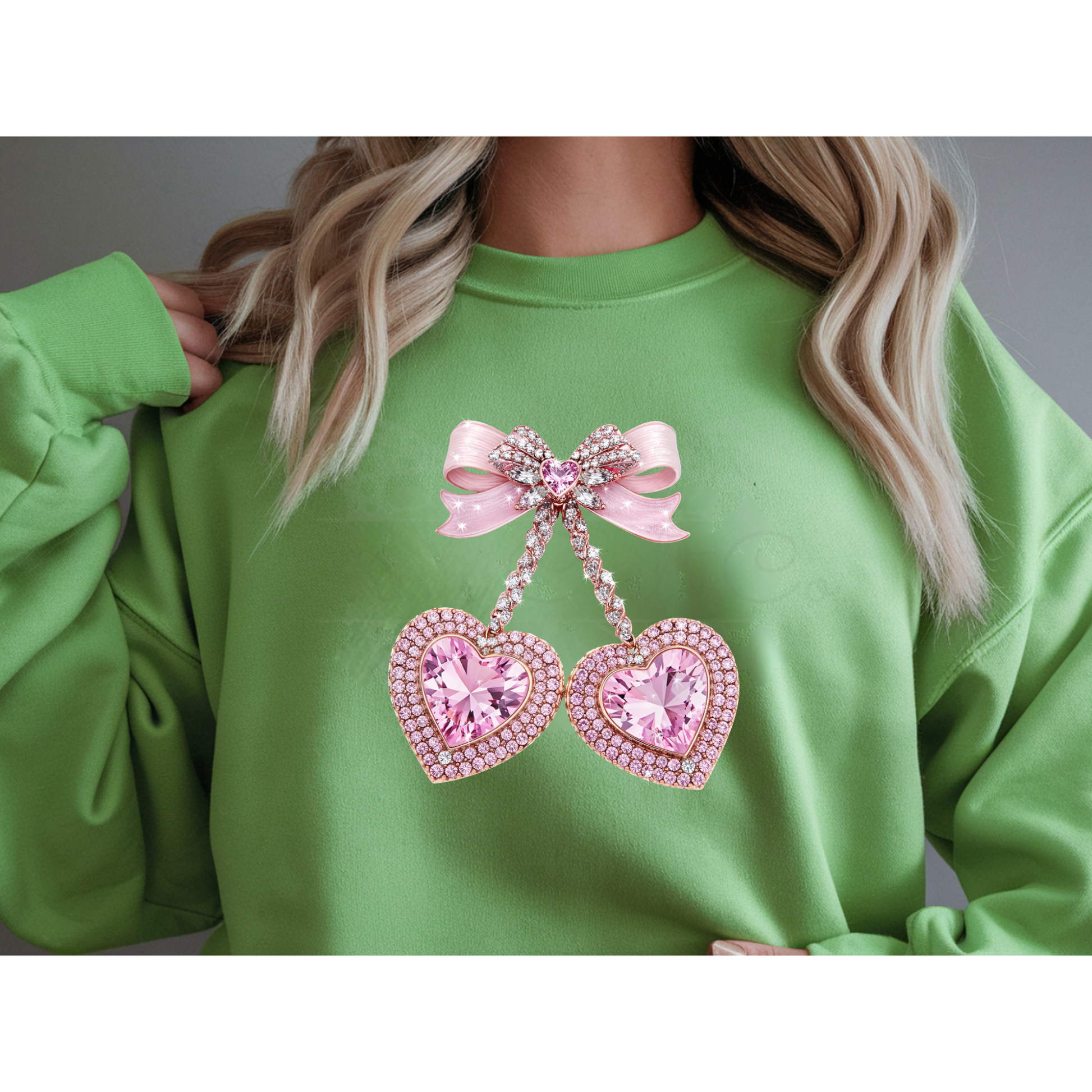 A mock up of a Green sweatshirt with pink heart faux rhinestone and bow design.