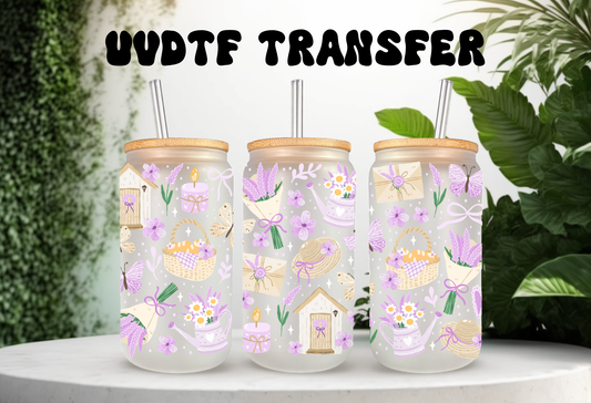 mockup of Three clear glass can tumblers with bamboo lids and glass straws, decorated with a pastel lavender and cottagecore garden pattern featuring lavender bouquets, birdhouses, candles, and butterflies, displayed on a clean white surface.