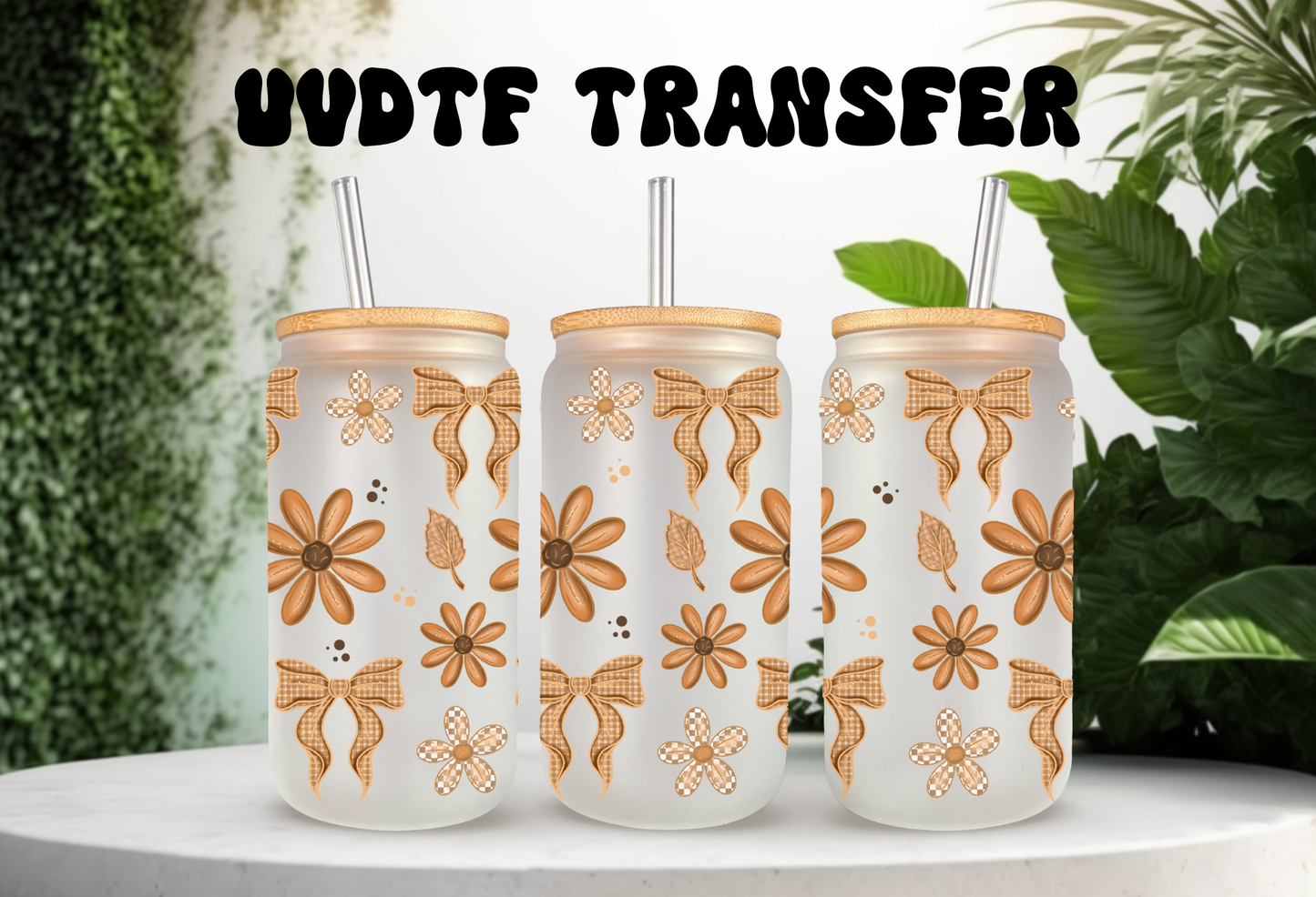 A mockup showcasing three frosted 16oz glass cans with bamboo lids and straws, decorated with orange daisy flowers and tan checkered bow UV DTF transfers