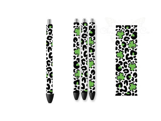 Mockup of four pens featuring green leopard print and shamrock UVDTF wraps next to a flat 1.5x4.7 inch decal design for St. Patrick's Day.