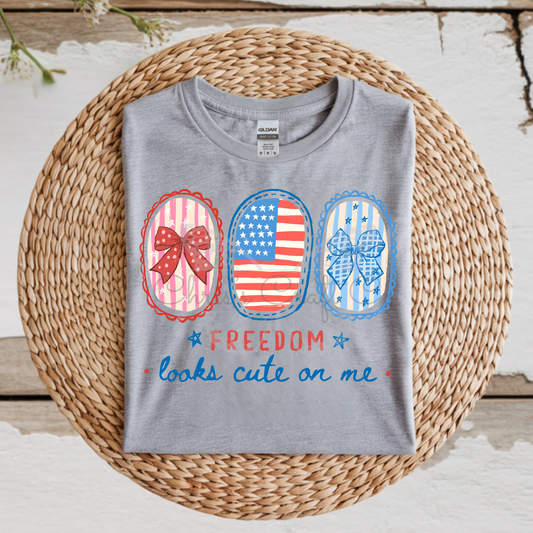 Patriotic coquette DTF transfer featuring the text 'Freedom looks cute on me' with a red bow, flag, and floral heart.