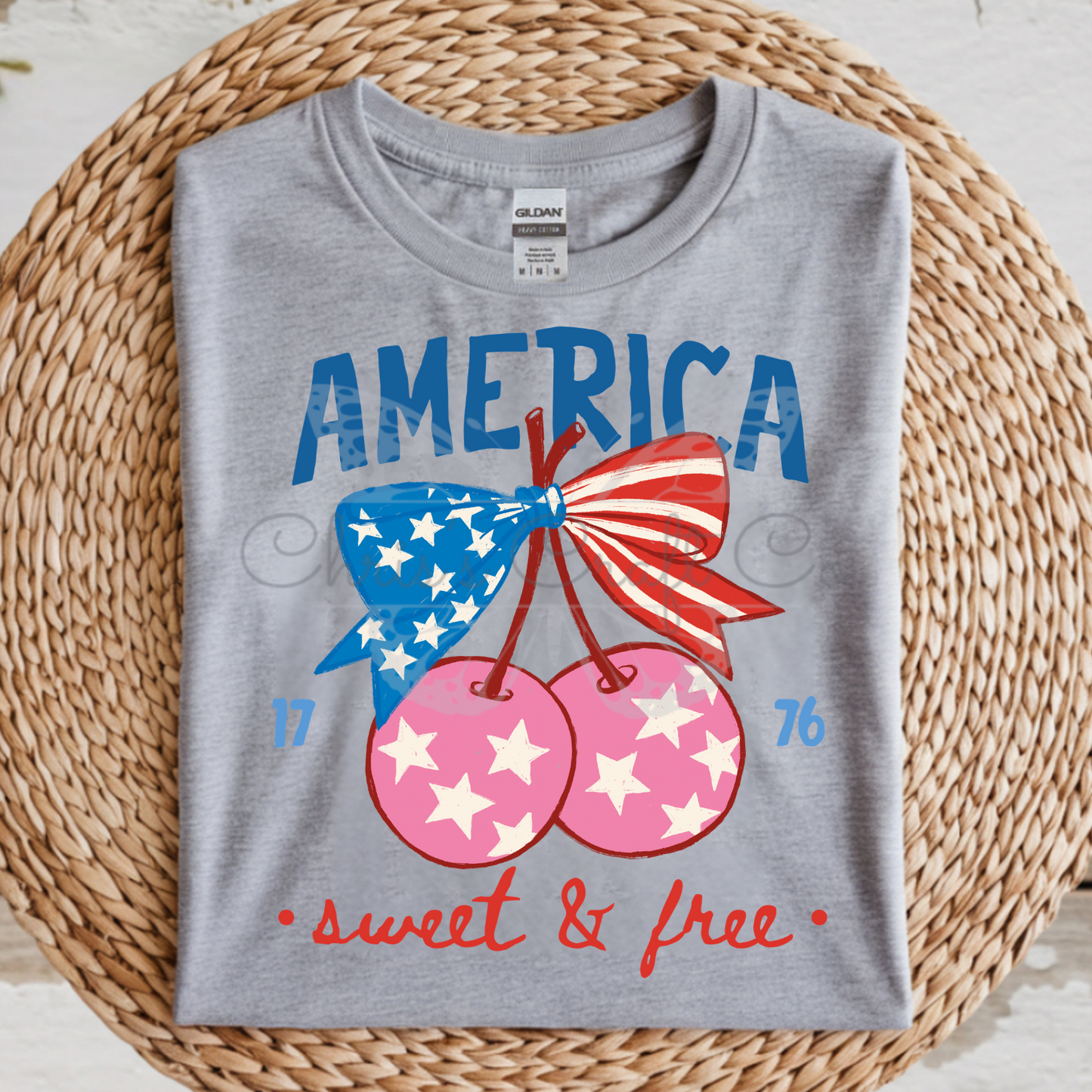 DTF shirt transfer featuring America text and two cherries with American flag and pink star patterns and a blue bow.

