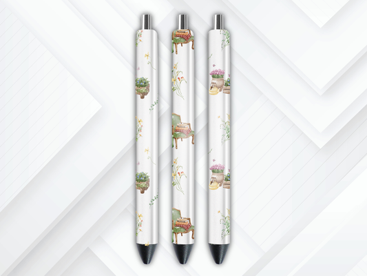 Pen wrap mockup featuring three white gel pens decorated with vintage reading armchairs, stacks of books, and potted botanical plants.