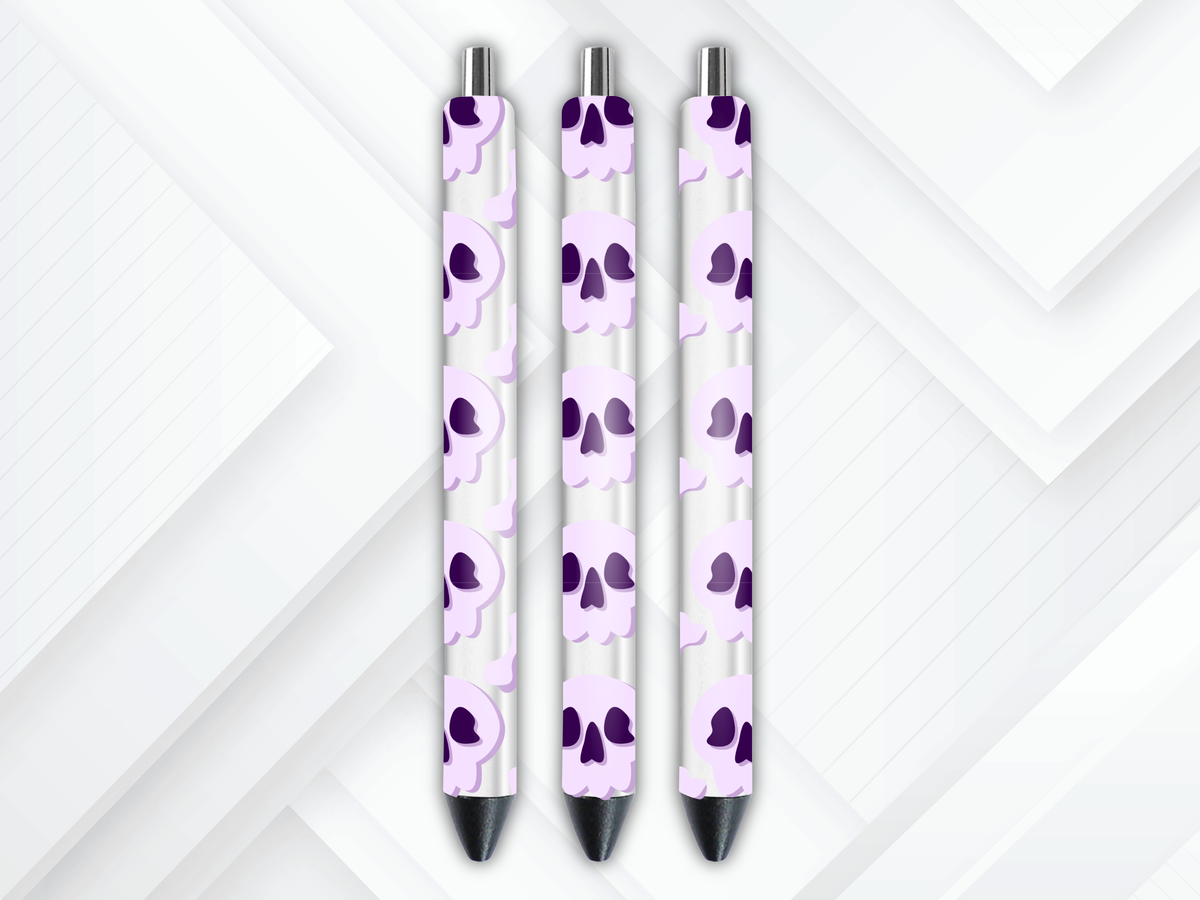 Pen wrap mockup featuring three white gel pens decorated with pastel purple skulls and bones UV DTF transfers.