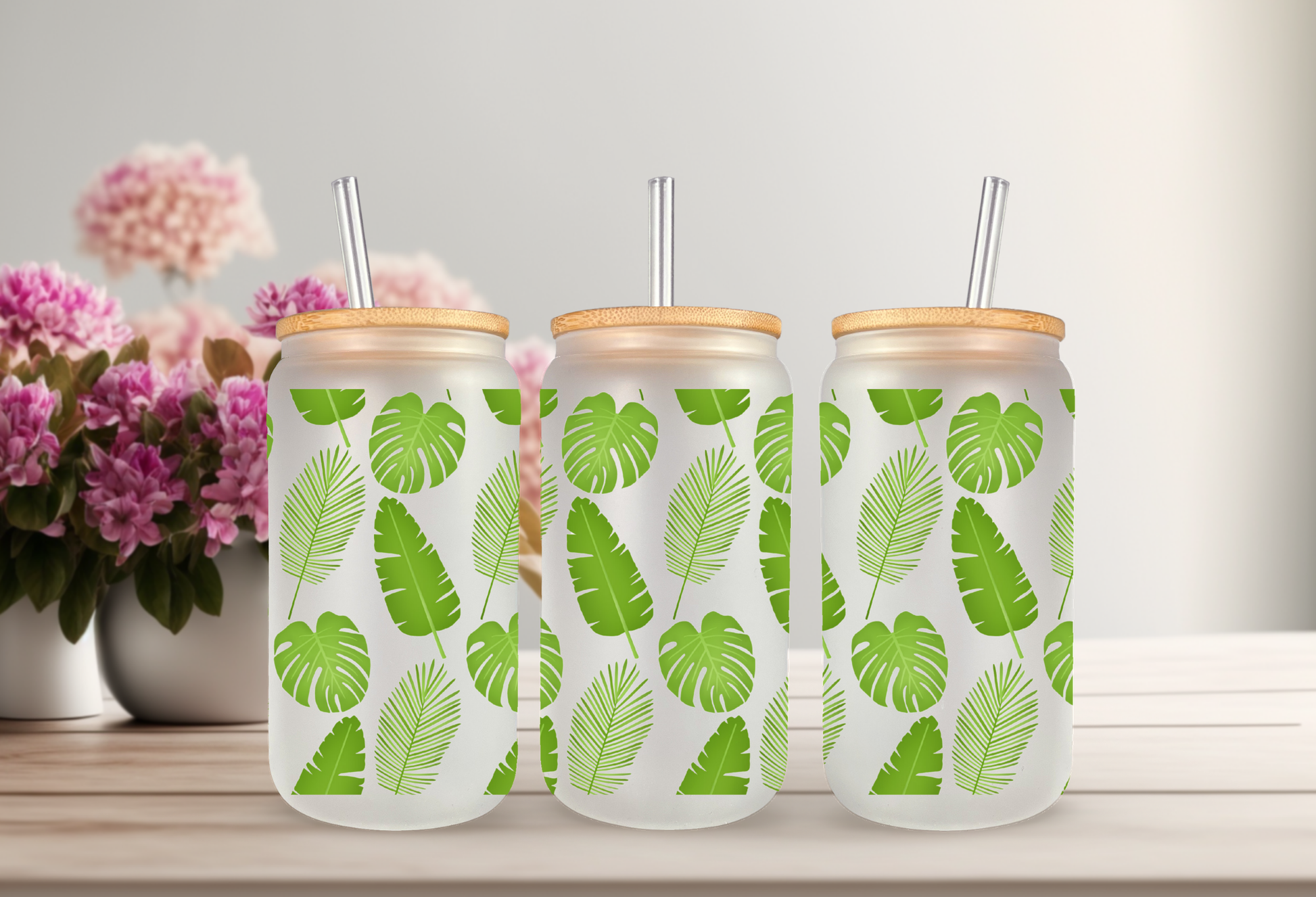 mockup of a 16oz frosted can glass wrap featuring a vibrant green botanical design with detailed monstera leaves and tropical palm fronds on a clear background.