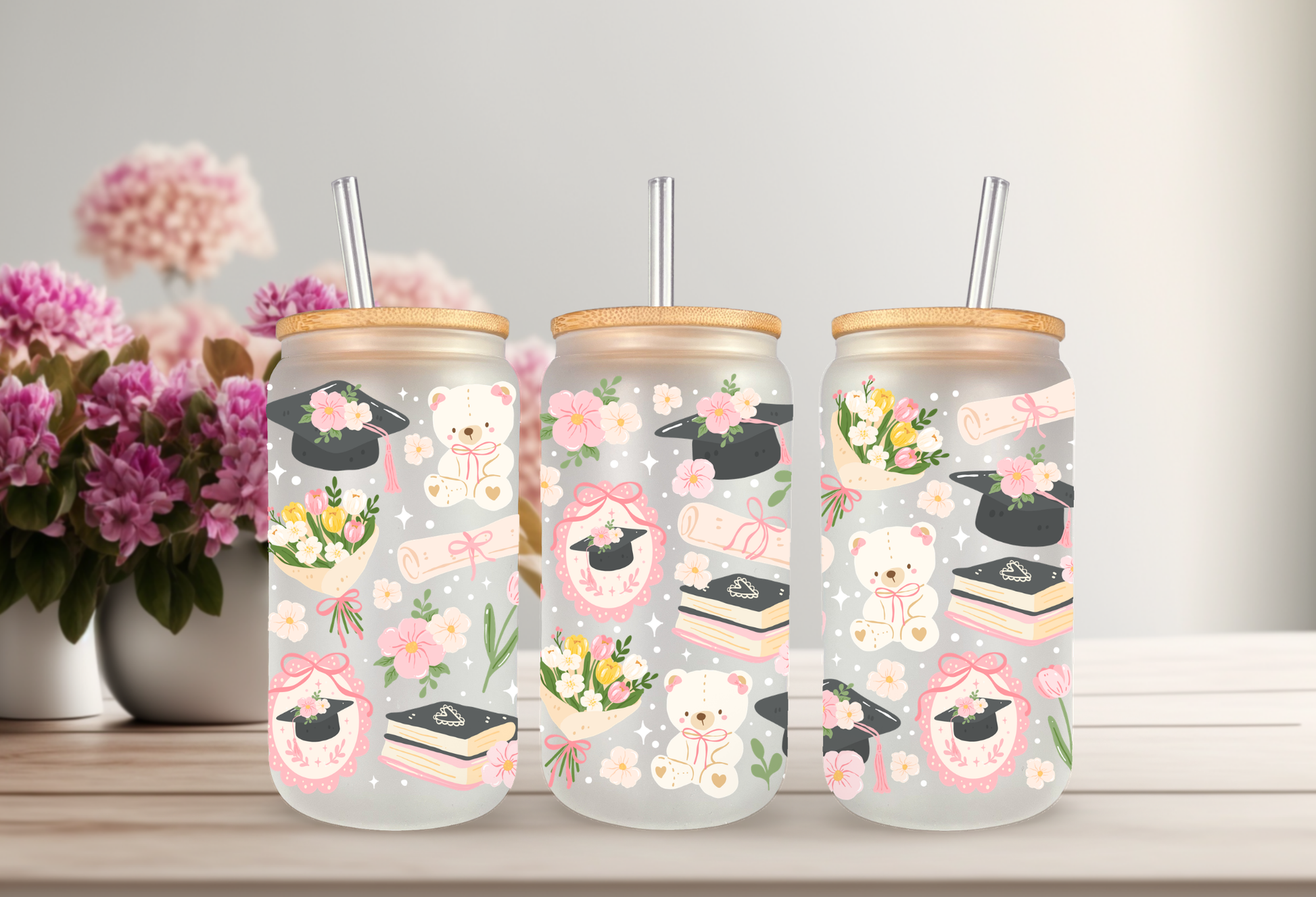 16oz can glass wrap featuring teddy bears in graduation caps, diplomas, stacks of books, pink coquette bows, and spring flowers on a clear background.