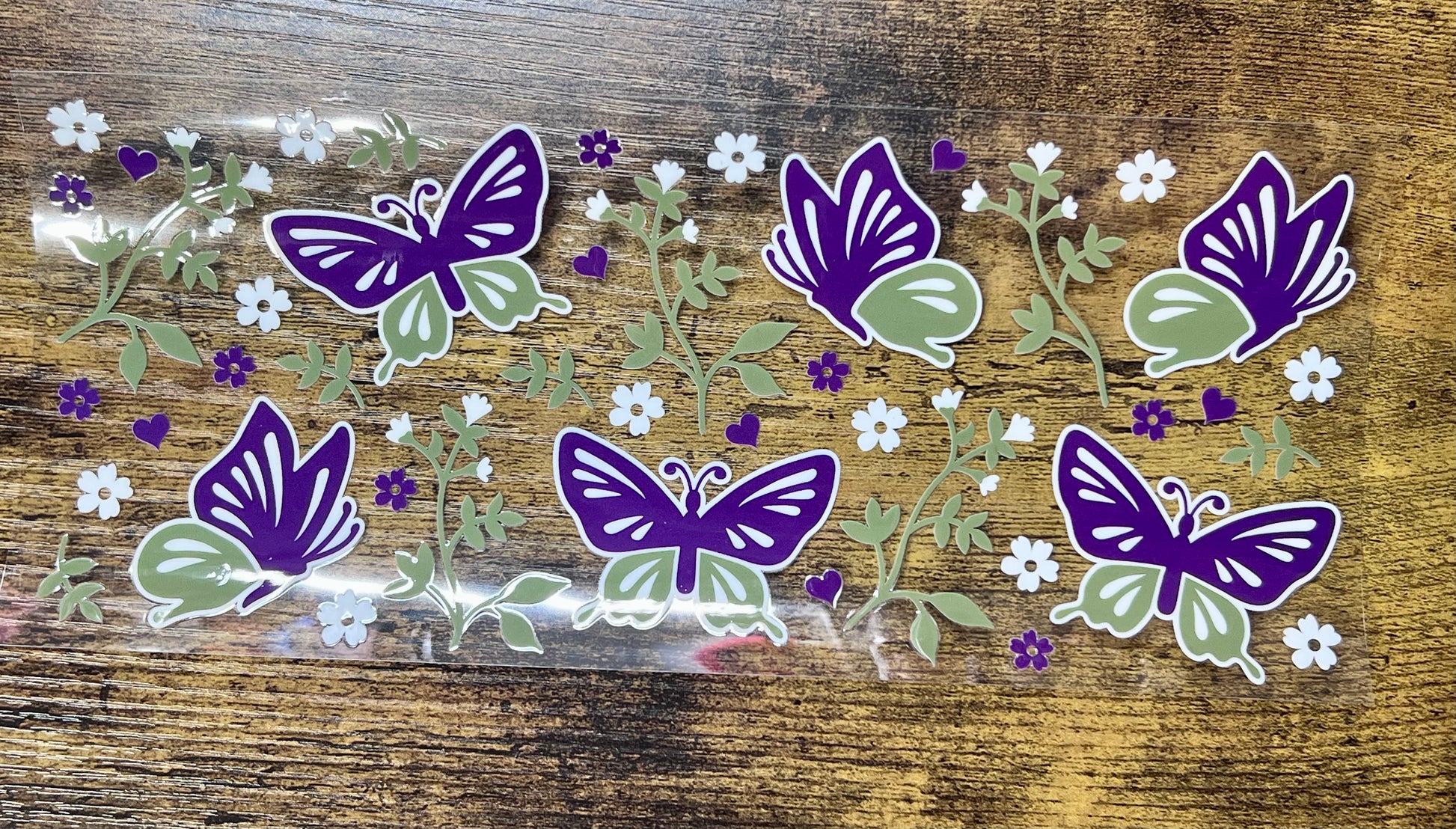 Purple and green butterfly stickers on a wooden surface