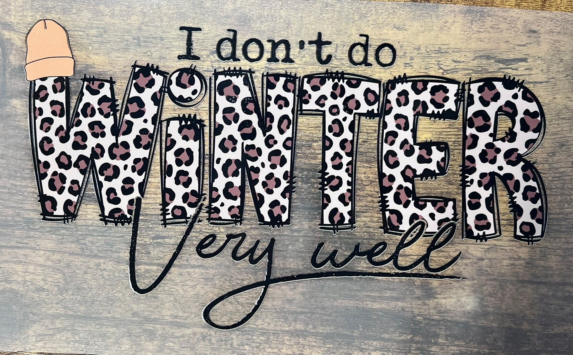 Text 'I don't do winter very well' with leopard print letters on a wooden background.
