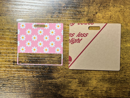 two different materials on a wooden surface, one with a pink floral pattern and the other with a plain white background.