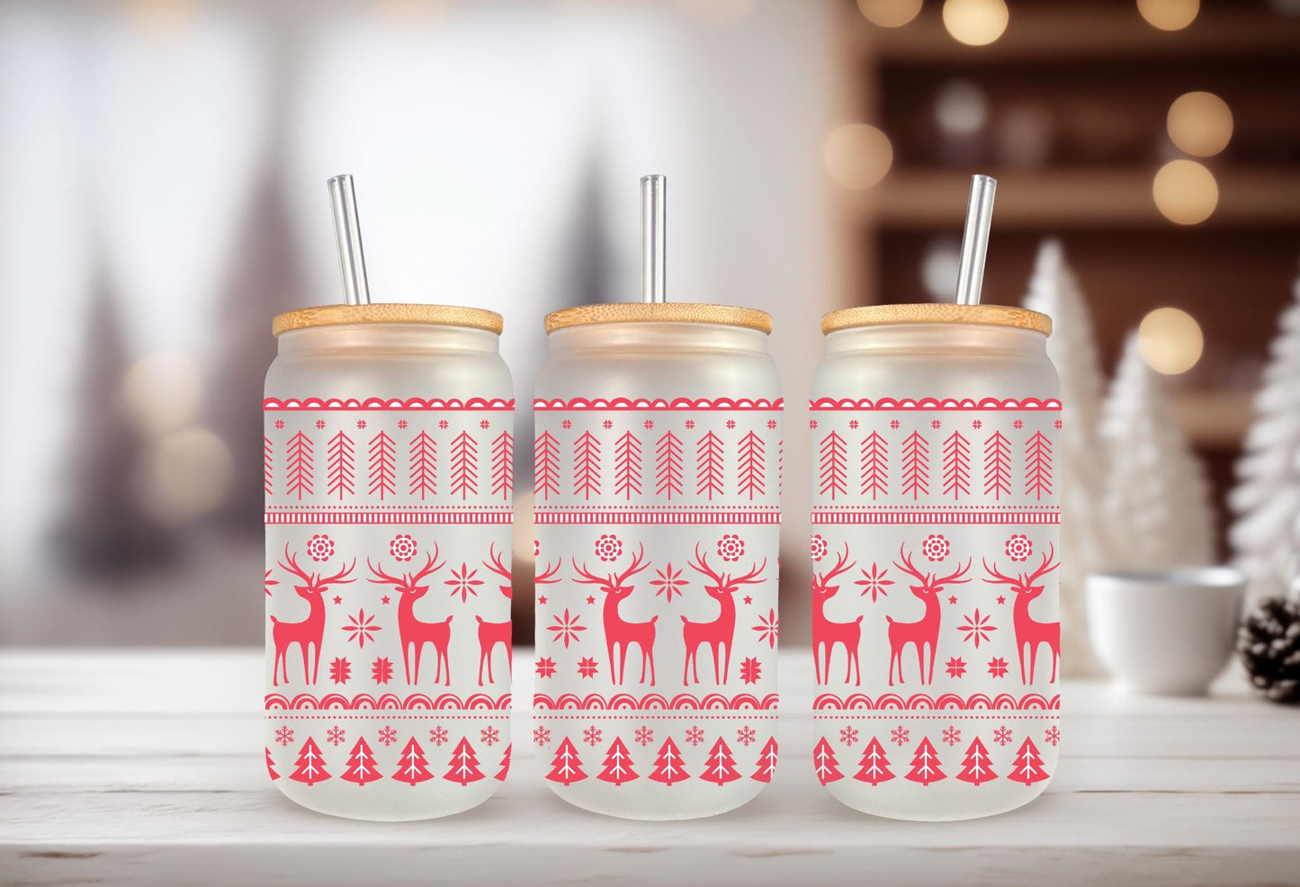 Three glass jars with a red and white Christmas-themed design, featuring reindeer and snowflakes, are displayed on a wooden surface.