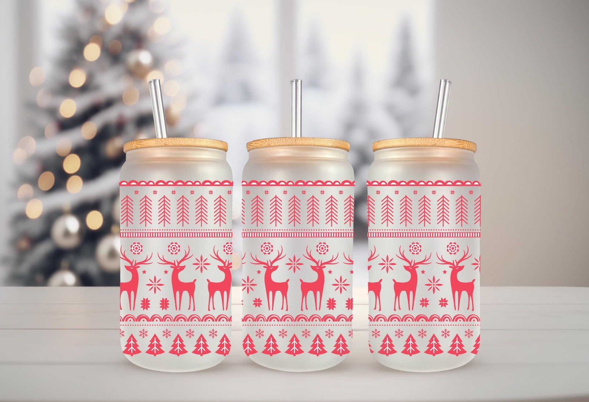 Three glass jars with red and white Christmas-themed designs, including reindeer and snowflakes, are arranged on a white surface.
