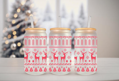 Three glass jars with red and white Christmas-themed designs, including reindeer and snowflakes, are arranged on a white surface.